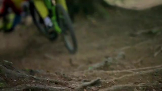Close-up slow motion shot of mountain bike jumping on single-track dirt trail.