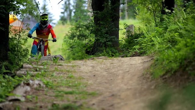 Two mountain bikers jumping on single-track dirt trail. Downhill riding.