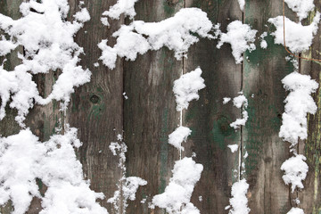 Fototapeta premium Snow on the wooden fence as a backdrop
