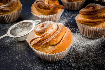 Modern fashionable pastries - scones cruffins  (puffmaffin), a mixture of a croissant and maffin. On blue dark wooden table, sprinkled with powdered sugar. Copy space