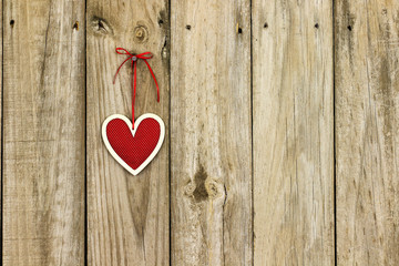 Red country heart hanging by ribbon on wooden background