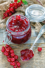 Jar and teaspoon with homemade red currant jam.