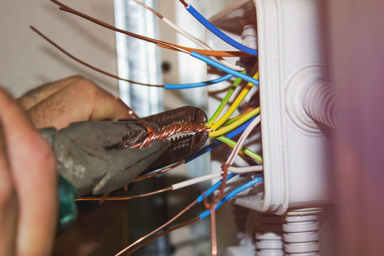 Electrician tightening the wire with pliers. installation works