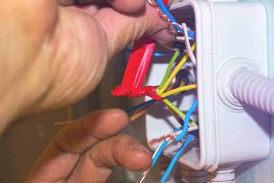 The electrician insulates the ends of the wires in the junction box