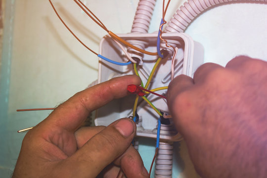 The electrician insulates the ends of the wires in the junction box