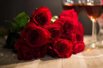 Red roses on a table with wine glasses in the background
