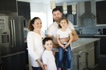 Fototapeta premium Portrait of a happy family of four in the kitchen at home