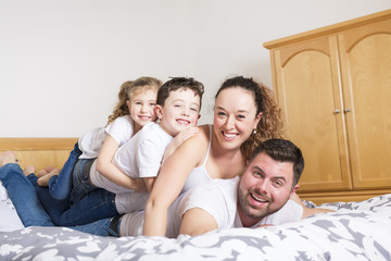 family, children and home concept - happy family with two kids under blanket at home