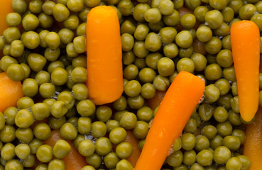 Carrots with green peas vegetable background.