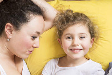 Mother and daughter at home in the bed.