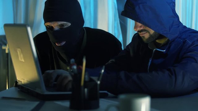 two thief hacker working on laptop in the night stealing data