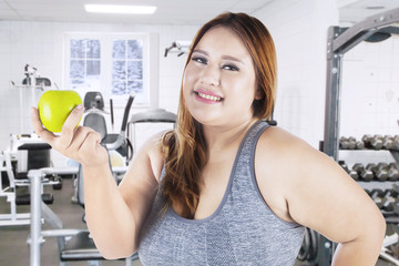 Fototapeta premium Overweight woman and apple in gym center