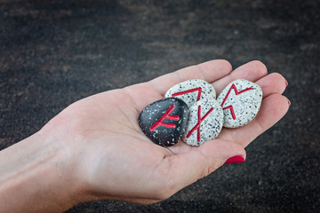  Scandinavian runes on the hand, futhark on dark background. Rune Fehu (Fehu), rune of wealth and...