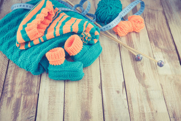 knitted green and orange children's set on wooden table