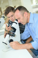 Naklejka na ściany i meble Man looking into eyepiece microscope