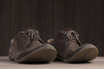 Brown suede shoes with brown laces on the background of dark natural wood.