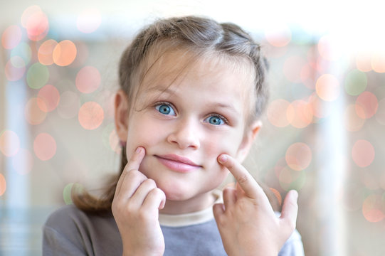 Portrait of a little girl who pokes his finger on the cheek 