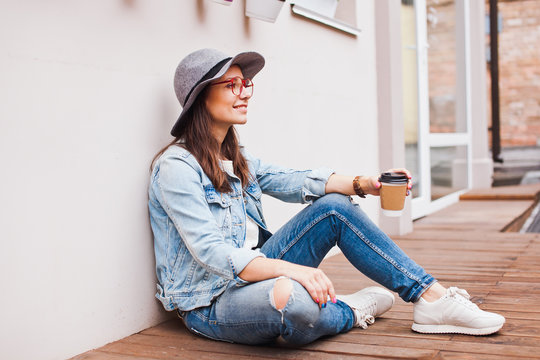 Young attractive hipster girl sits on terrace with coffee