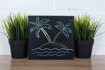 Two palm trees on an island hand drawn in chalk on a blackboard 
