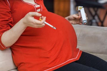 Smoking in pregnancy. Bad pregnant mother holds cigarette in hand.