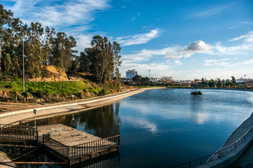 Lake of the park Moret with the blue sky and white clouds. The park is the biggest green space of the city of Huelva in Spain