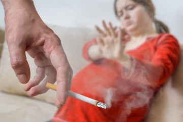 Passive smoking in pregnancy. Selfish man is smoking cigarette. © vchalup