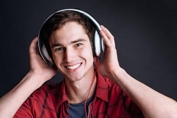 Delighetd smiling young man listening to music