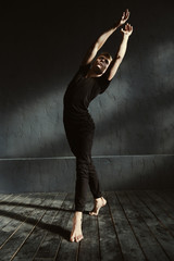Talented young guy dancing in the black colored studio