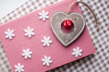 White christmas snowflakes and wooden heart decoration on pink background. Winter wallpaper. Top view