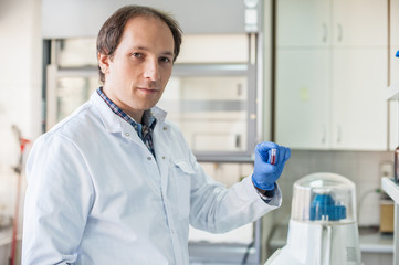 Male lab technician holding a test tube with sample