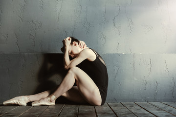 Exhausted ballet dancer crying in the dark lighted room