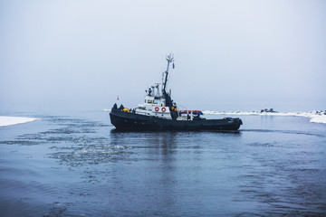The russian Icebreaker tug boat ship trapped in ice tries to break free and leave the bay between the glaciers
