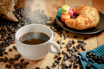 Hot coffee cup and breakfast baked croissants on wooden background