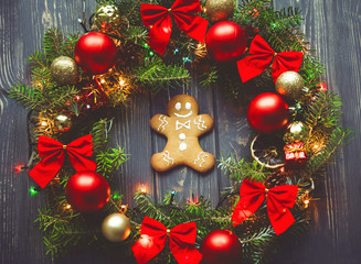 Gingerbread men inside of Christmas wreath on wooden background.