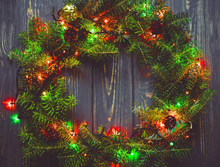 Christmas wreath handmade with lights of garland on a wooden bac