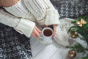 Woman holds a cup of tea beside her legs