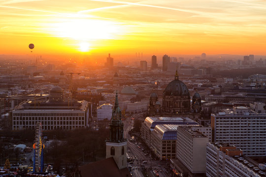 Beautiful panoramic aerial view over Berlin (Berlin Cathedral - Berliner Dom, City Palace - Stadtschloss, Potsdamer Platz, Bundestag - Reichstag) with romantic colorful sunset and balloon in the sky.