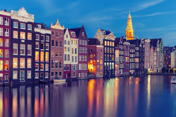 Amsterdam canal with typical houses and Oude Kerk church during twilight blue hour, Holland, Netherlands. Used toning