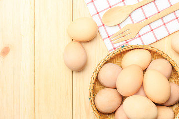 Fresh egg in the basket weaving over wooden table background, Top view with copy space and text.