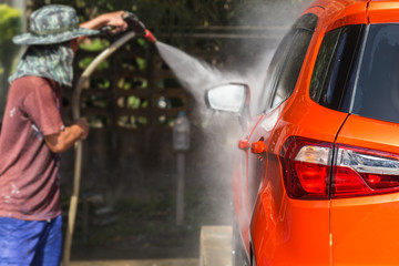 Man spraying pressure washer for car wash in car care shop. Focu