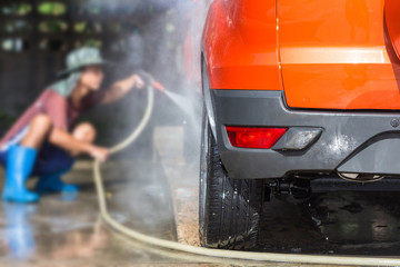 Man spraying pressure washer for car wash in car care shop. Focu