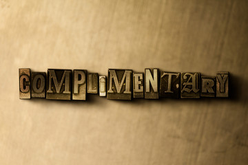 Naklejka premium COMPLIMENTARY - close-up of grungy vintage typeset word on metal backdrop. Royalty free stock illustration. Can be used for online banner ads and direct mail.