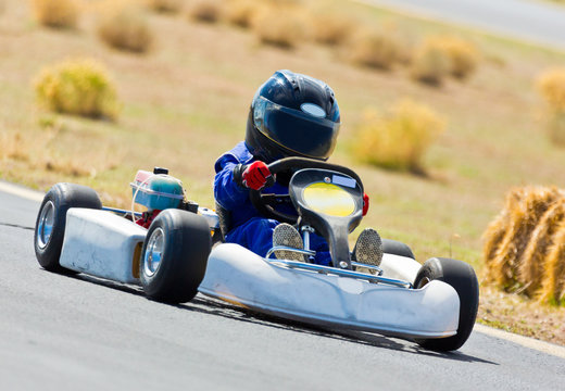 Young Kid Racing A Go Cart Around A Track.