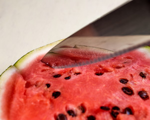 knife cutting a piece of ripe watermelon
