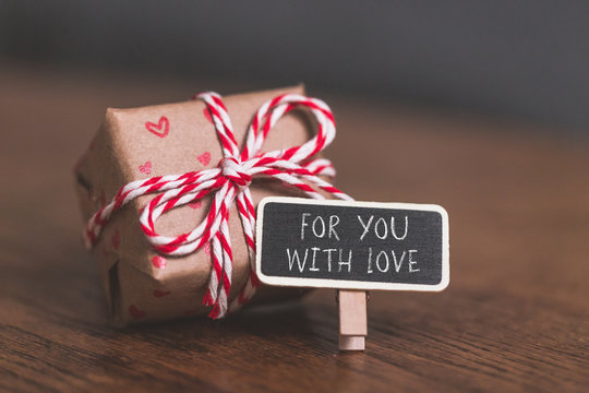 Gift, present and little blackboard with text: For You with Love on wooden table.