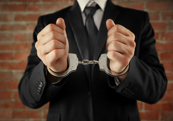 Man in handcuffs on brick wall background