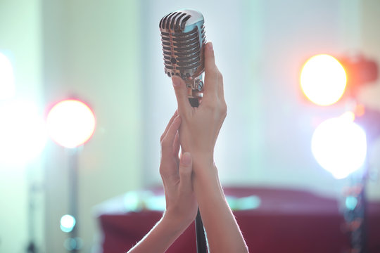 Female hands holding retro microphone, close up
