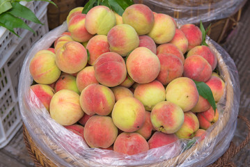 Fresh peaches in a wooden basket at the fruit market
