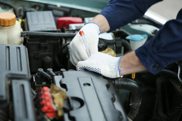 Fototapeta na wymiar Mechanic hands in gloves repairing car in open hood