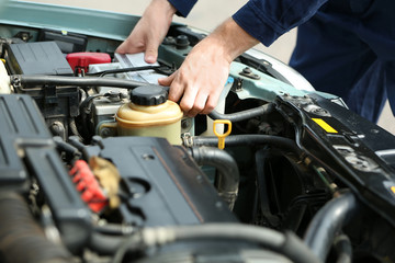 Mechanic hands checking up of serviceability of the car in open hood, close up